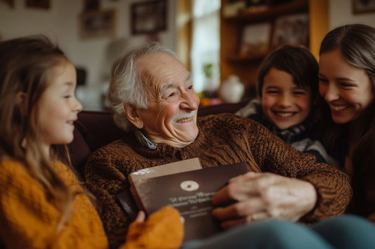 Grand-père souriant, entouré de ses petits-enfants, tenant un livre de souvenirs, symbole de transmission familiale.